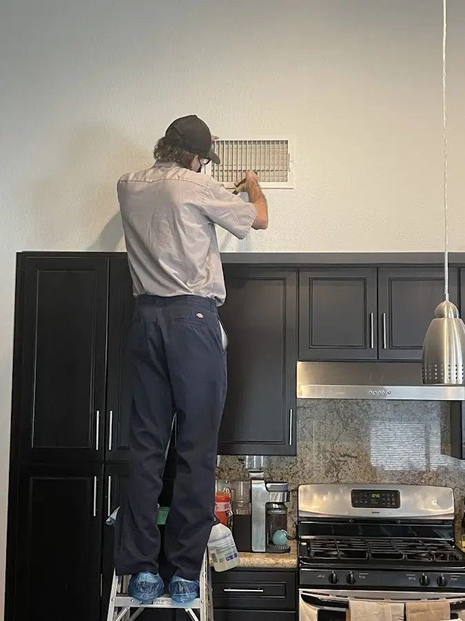 Technician inspecting an air vent during HVAC service in Upper St. Clair